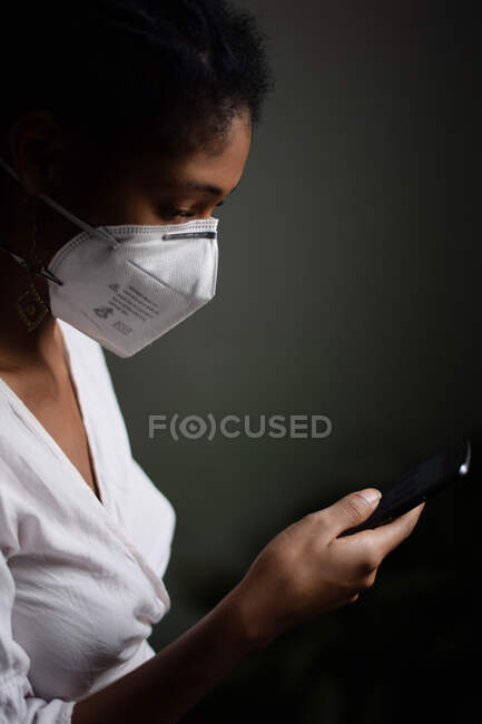 Femme avec masque facial utilisant un smartphone — Photo de stock