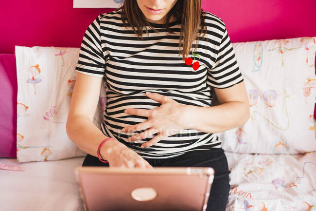 Анонімна вагітна жінка працює з планшетом вдома — стокове фото