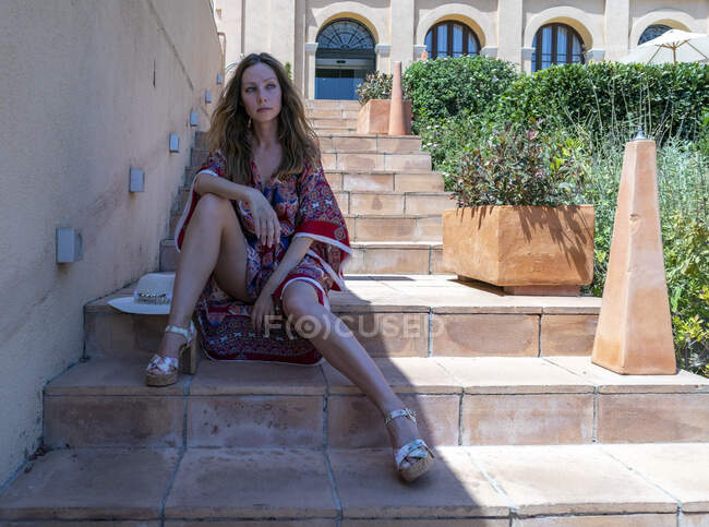 Chica rubia posando en verano con un vestido junto a la piscina - foto de stock