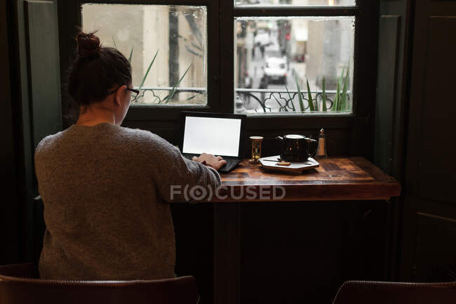 A young student works on a table near a pub window — Stock Photo