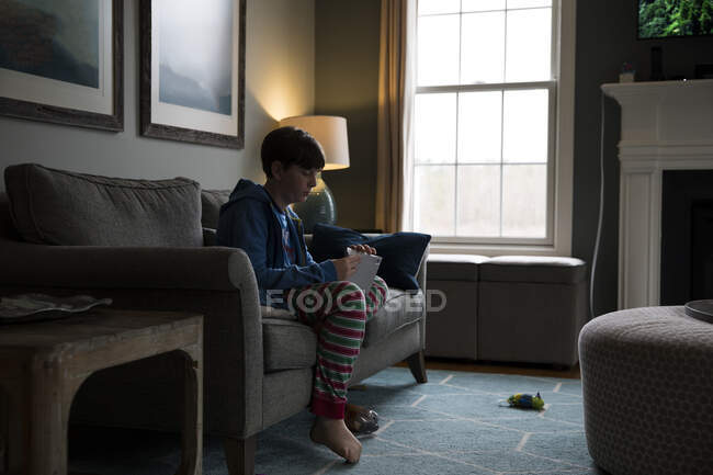 Side Silhouette of Teen Boy Sitting on Couch Opening A Letter — Stock Photo
