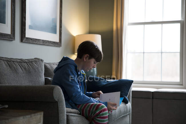 Close Up Side View of Teen Boy Sentado no sofá leitura de cartão de aniversário — Fotografia de Stock