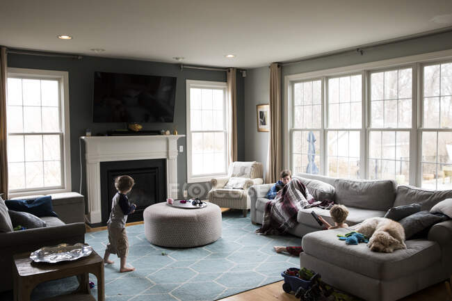 Ampla vista dos irmãos com gripe em sua sala de estar com cão — Fotografia de Stock