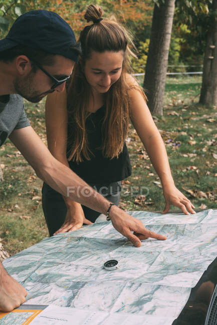 Menino e menina planejando a rota em um mapa e uma bússola — Fotografia de Stock