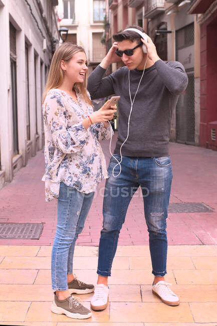 Atractivo joven pareja escuchar música con auriculares en th - foto de stock