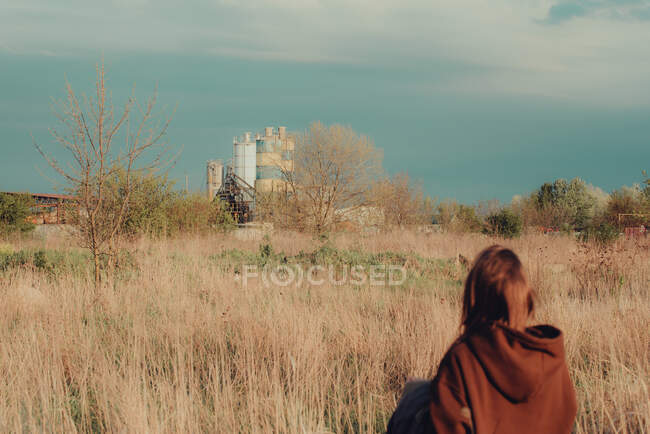 Persona in felpa con cappuccio marrone in piedi in campo vicino alla pianta — Foto stock