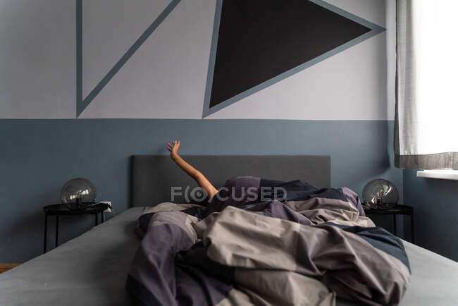 Plan moyen de la femme se prélassant sur le lit pendant la première lumière du matin. — Photo de stock