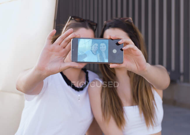 Deux amis tiennent le téléphone dans leurs mains pour faire un selfie — Photo de stock