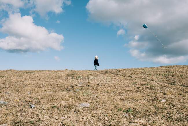 Kleiner Junge lässt an einem sonnigen Tag einen Drachen auf einem Hügel steigen — Stockfoto
