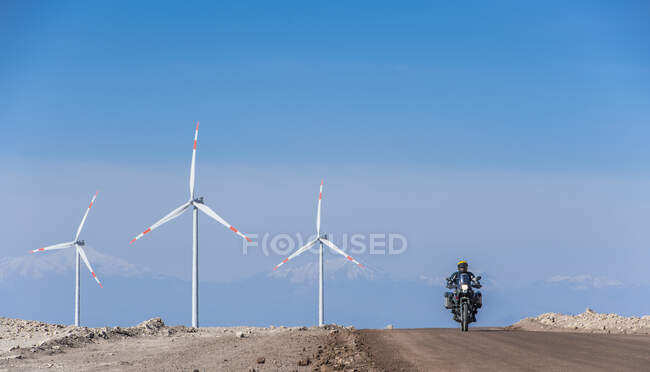 Hombre montando su moto ADV en el parque eólico en el remoto desierto de Atacama - foto de stock