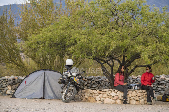Two women sitting beside motorbike camp at the Ruinas de Quilmes — Stock Photo