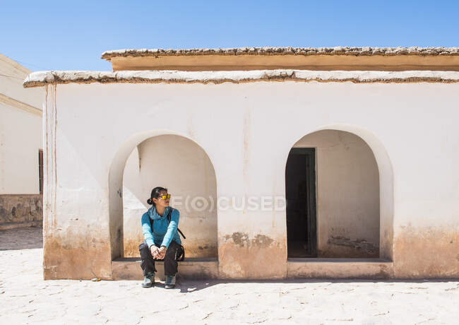 Mujer esperando en arco en pequeño pueblo en Purmamarca / Argentina - foto de stock