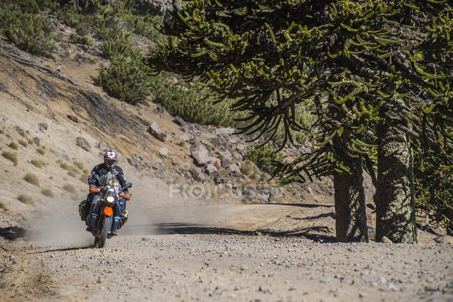 Hombre en motocicletas de turismo conduciendo por carretera de grava en Argentina - foto de stock