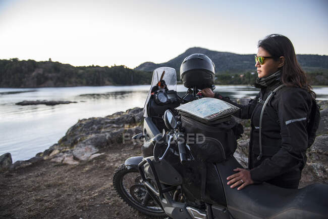 Woman standing next to touring motorbike at Lago Alumine in Argentina — Stock Photo