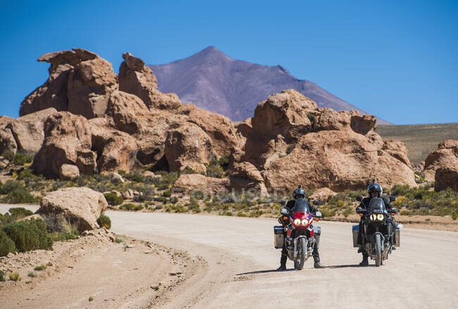 Two friends riding touring motorcycle's on dusty road in Bolivia — Stock Photo