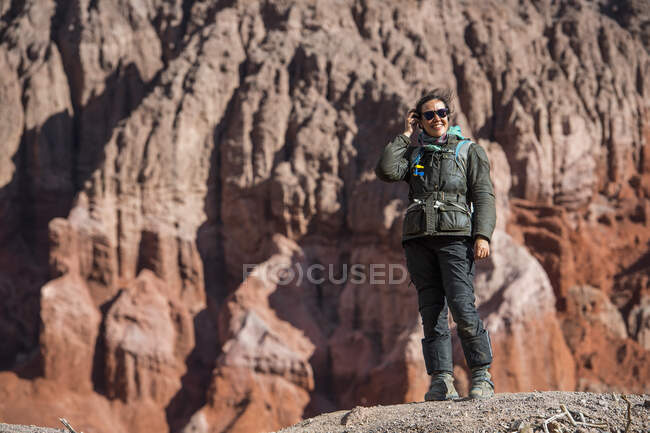 Женщина в мотоциклетной экипировке, стоящая перед образованием красного песчаника — стоковое фото