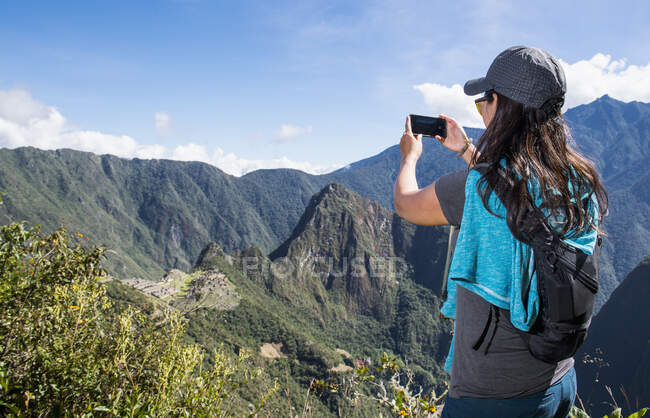 Mujer toma una foto en el smartphone de Machu Picchu en el Camino Inca - foto de stock