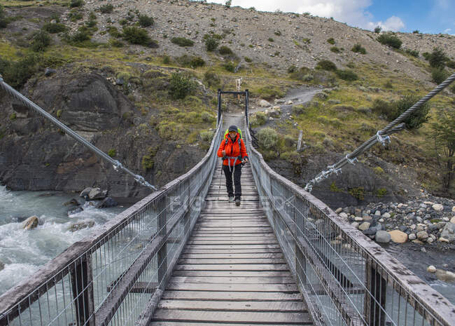 Femme randonneuse traversant le pont au parc national Torres del Paine — Photo de stock