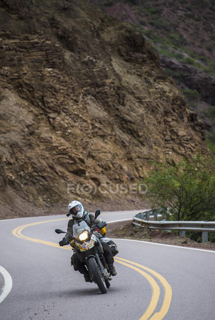 Woman on touring motorbike riding twisting road in Argentina — Stock Photo