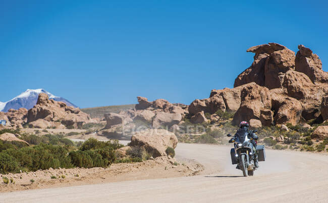 Homem andando de moto em turnê na estrada empoeirada na Bolívia — Fotografia de Stock