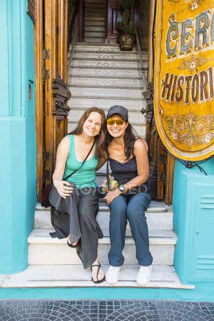 Two female friends sitting at the entrance of house in Buenos Aires — Stock Photo