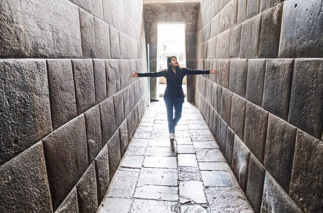 Woman stretching her arms between ancient Inca walls, Cusco, Peru — Stock Photo