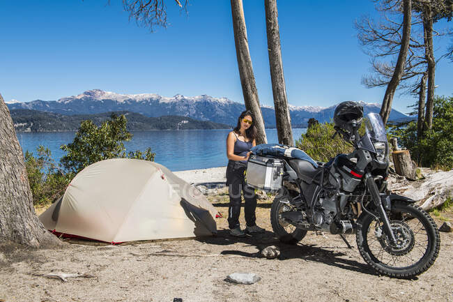 Mujer empacando motocicleta en el campamento en el lago Nahuel Huapi en Patagonia - foto de stock