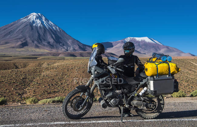 Woman behind ADV motorbike, in front of the stratovolcano Licancabur — Stock Photo