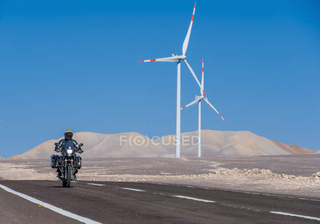 Homme conduisant sa moto ADV au parc éolien dans le désert lointain d'Atacama — Photo de stock