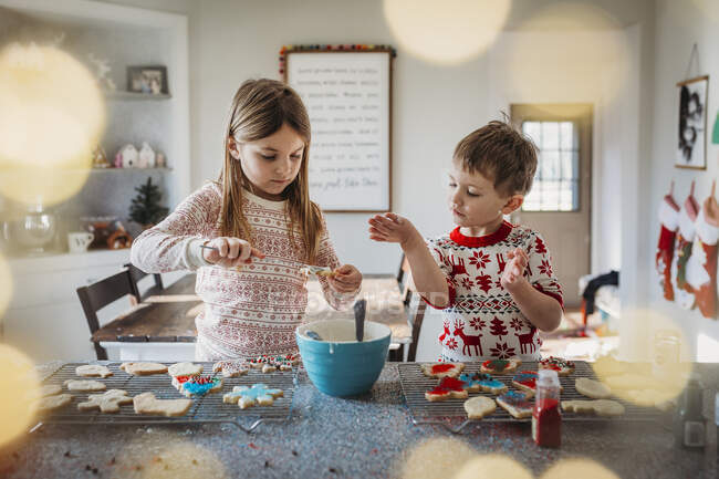 Niños y niñas hermanos decorando galletas de Navidad - foto de stock