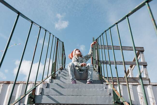 Young girl sitting on the stairs shouting out loud whilst outside — Stock Photo