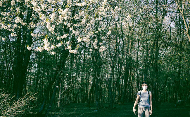 Mulher vestindo máscara médica na floresta de primavera — Fotografia de Stock