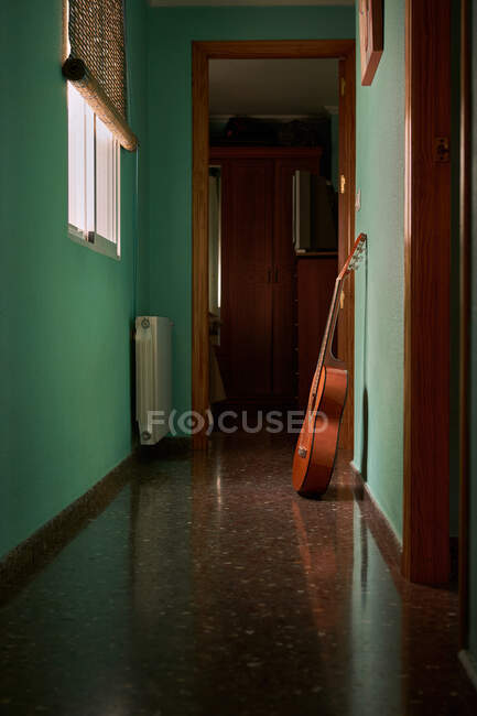 A guitar is leaning against the wall of a hallway in a house — Stock Photo