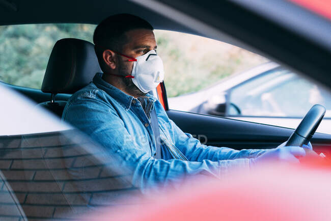 Hombre con máscara y guantes conduciendo un coche. Concepto de conducción y COVID-19 . - foto de stock