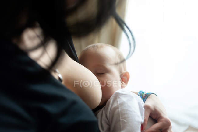 Mutter stillt ihr Baby am Fenster — Stockfoto