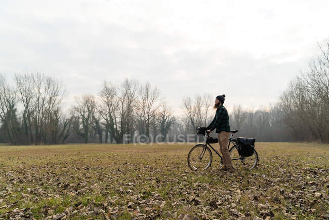 Establishing shot of man pushing touring bicycle at a landscape, Croat — Stock Photo