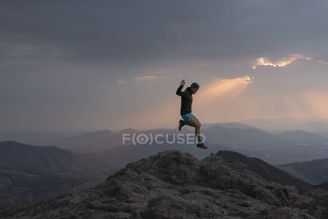 Un uomo che salta tra le rocce mentre il sentiero corre al tramonto — Foto stock