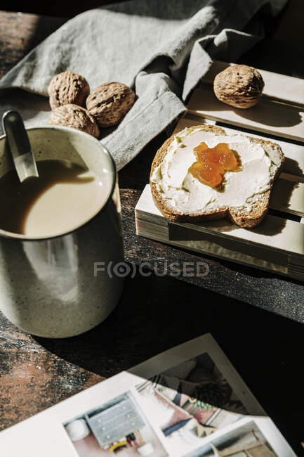 From above of tasty bread toast with butter and jam on a table with walnuts and fresh coffee alongside a magazine — Stock Photo