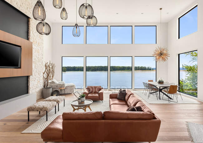 Hermosa sala de estar en una nueva casa de lujo moderna. Características techos abovedados, chimenea con fuego rugiente, y hermosa vista exterior del agua - foto de stock