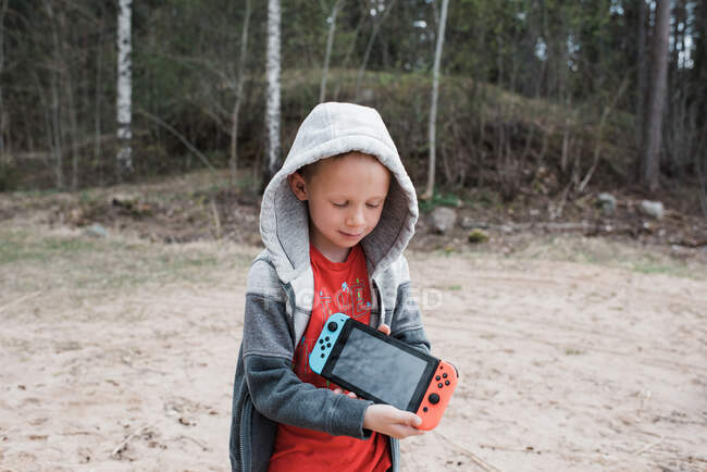 Jeune garçon tenant une console de jeux Nintendo partageant l'écran — Photo de stock