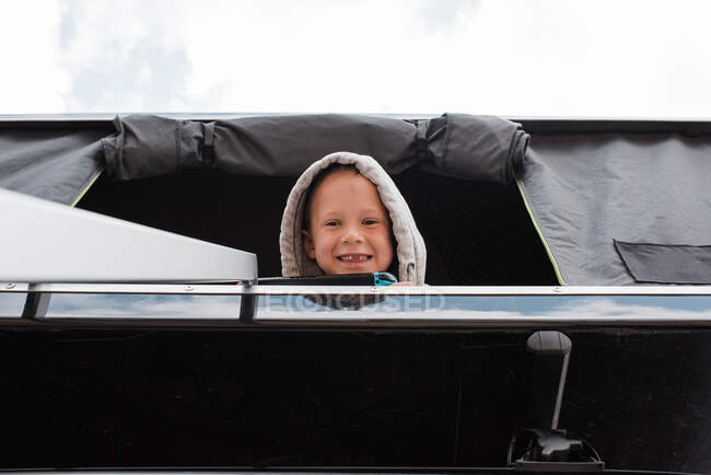 Junge lächelt beim Zelten vom Dachzelt — Stockfoto