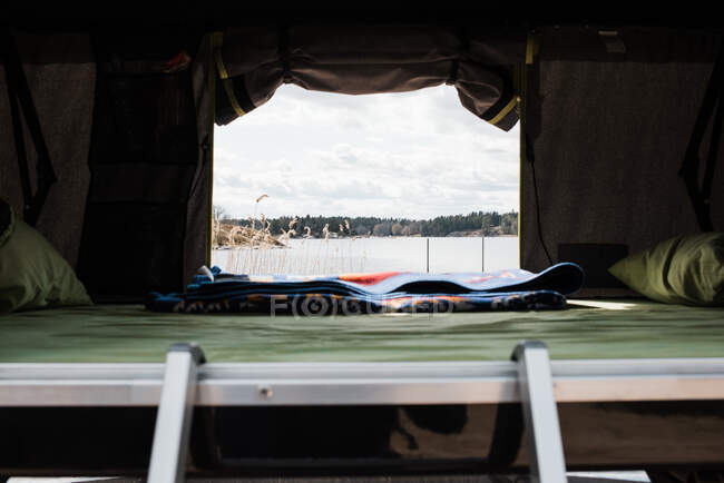 View of a lake from the window of a roof top tent — Stock Photo