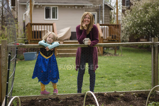 Uma mãe e uma menina em carrinho de vestido de princesa na borda do jardim — Fotografia de Stock