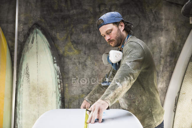 Молодой человек делает доску для серфинга. — стоковое фото