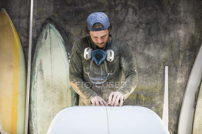 Junger Mann bastelt Surfbrett. — Stockfoto