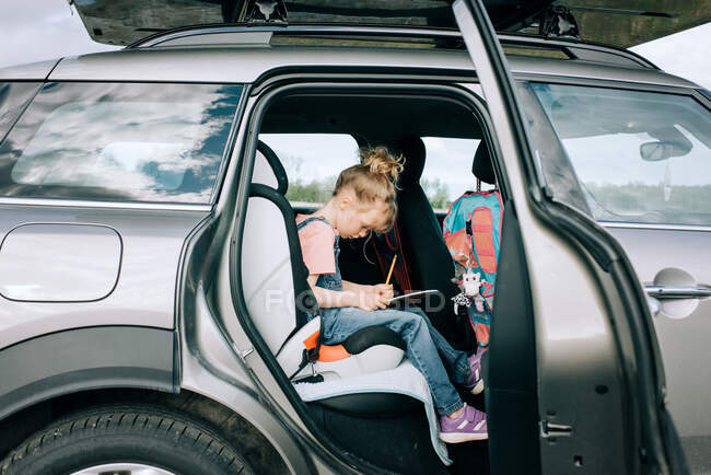 Jovem menina sentou-se desenho no carro em uma viagem de carro — Fotografia de Stock