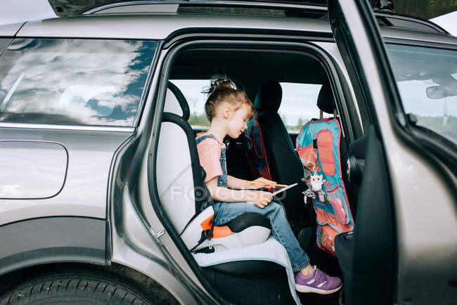 Girl sitting in the car drawing pictures feeling happy — Stock Photo