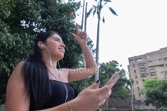Жінка слухає музику через мобільний пристрій, рухаючи руками  . — стокове фото