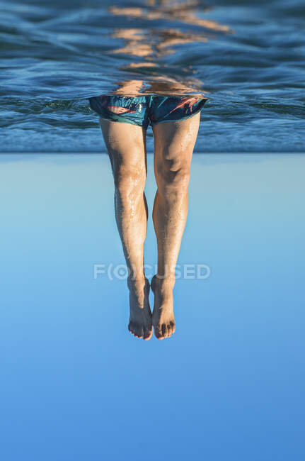 Jovens pernas masculinas a sair da água. Surrealismo — Fotografia de Stock