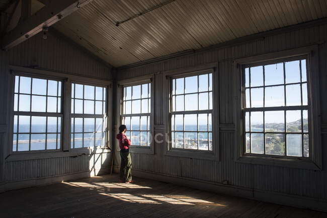 Eine Frau beobachtet durch einige Fenster ein altes Gebäude. / — Stockfoto
